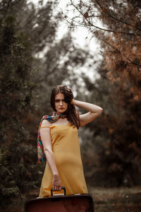 Portrait of young woman standing against trees