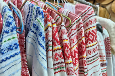 Traditional russian national bright ornaments on woven dresses hanging on hangers.