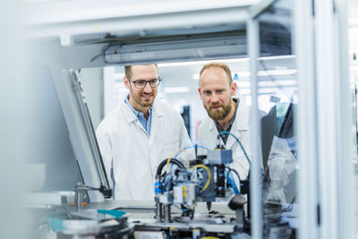 Colleagues in electronics factory watching machine work