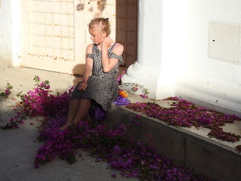 Full length of girl sitting by purple flowers
