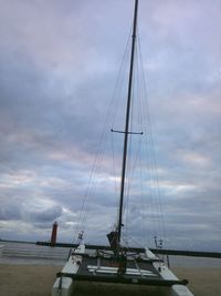 Sailboat in sea against cloudy sky