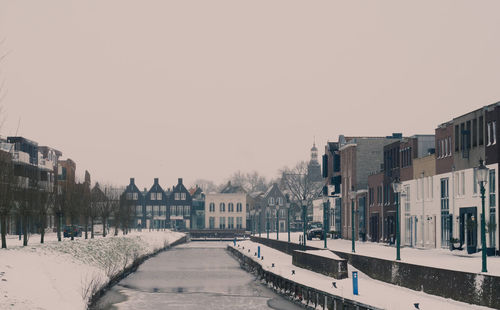 Road amidst buildings against sky during winter