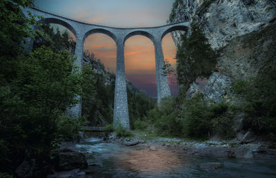 Bridge over river in forest against sky