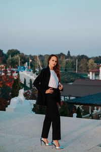Young woman in black trouser suit and silver shoes on the background of the park