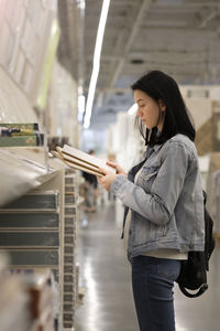 Beautiful young woman chooses flooring in a hardware store to make repairs in the apartment. 