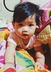 Portrait of cute baby girl on bed at home