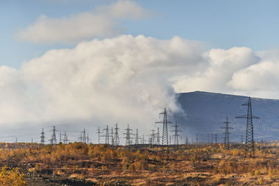 Scenic landscape of power lines and pylons located in field in autumn on sunny day in highland area