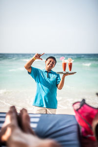 Full length of man sitting at beach against sky