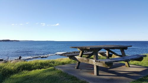 Empty picnic table against sea