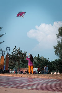 Rear view of girl flying kite in city