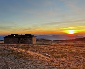 Built structure on field against sky during sunset