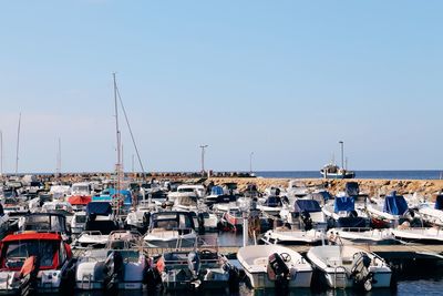 Sailboats moored at harbor against clear blue sky