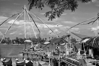 Boats moored at harbor against sky in city