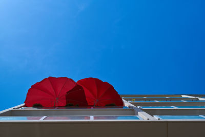 Directly below shot of red umbrella against blue sky