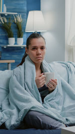 Young woman using mobile phone while sitting at home