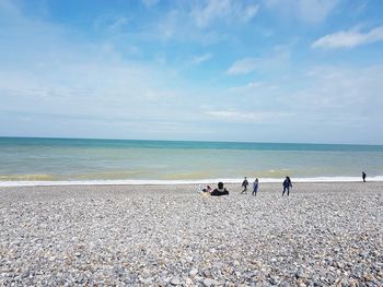 People at beach against sky