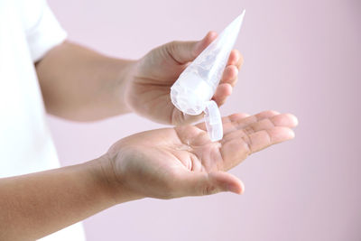 Close-up of woman holding hands over white background