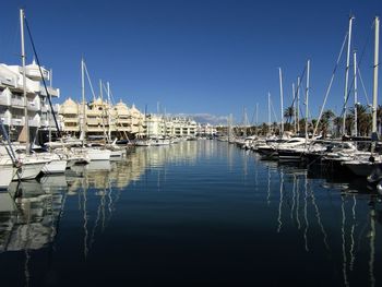 Sailboats moored in harbor against clear blue sky