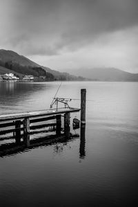 Wooden posts in lake against sky