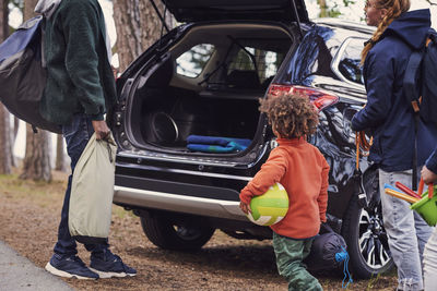 Family unloading car trunk at campsite