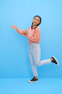 Portrait of young woman standing against blue sky