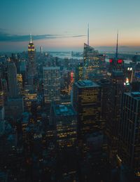 Illuminated buildings in city against sky at dusk