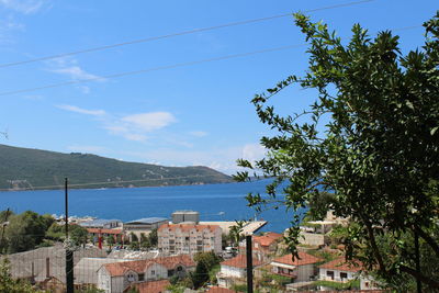 Buildings by sea against blue sky