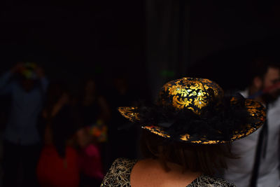 Rear view of woman wearing hat at night