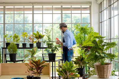 Woman holding potted plant by window