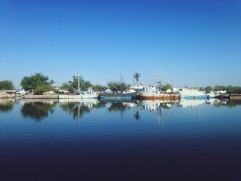 Boats moored in sea against clear blue sky
