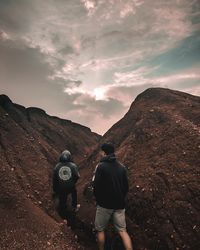 Rear view of men standing on mountain against sky