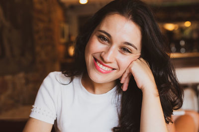 Close-up portrait of smiling young woman sitting in restaurant