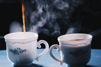 Close-up of tea being poured in cup on table