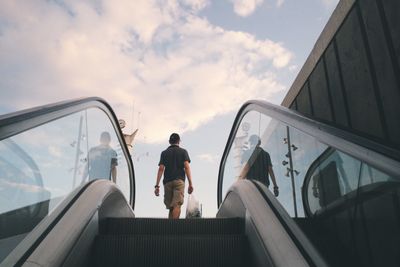 Low angle view of man moving up on escalator