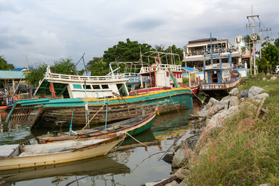 Boats moored by trees against sky