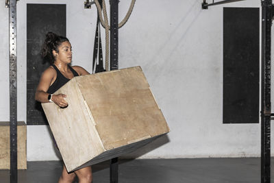 Latin woman picking up a box to do crossfit