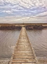 Boardwalk amidst water against sky