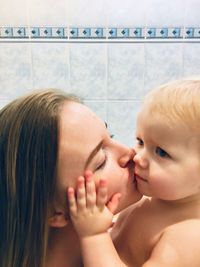 Mother kissing daughter while in bathroom at home