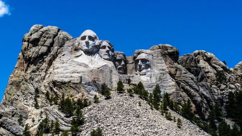 Low angle view of rocky mountains against blue sky at mount rushmore national memorial