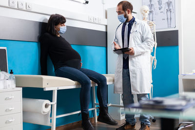 Doctor wearing mask examining pregnant woman in hospital