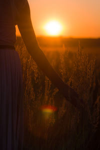 Man standing on field against bright sun during sunset