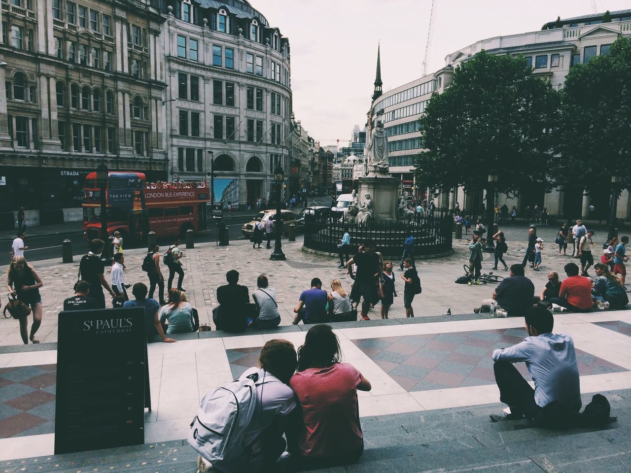 building exterior, large group of people, architecture, street, city, built structure, men, person, city life, transportation, land vehicle, lifestyles, car, walking, city street, mode of transport, road, mixed age range, leisure activity