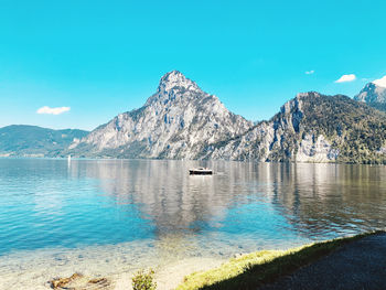 Scenic view of lake and mountains against blue sky