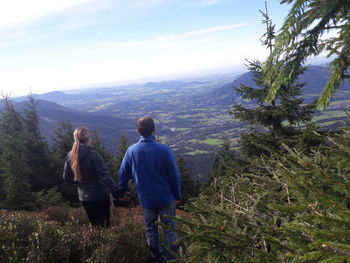 Rear view of couple walking on mountain against sky