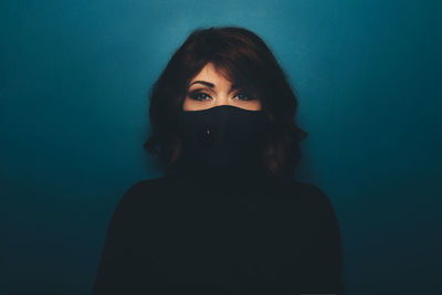 Portrait of woman wearing mask against colored background