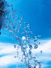 Close-up of water splashing against blue sky