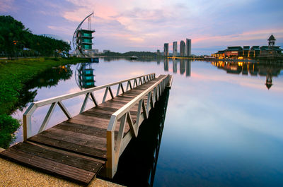 Jetty on lake against sky during sunrise. mirror reflection of modern architecture on lake surface.