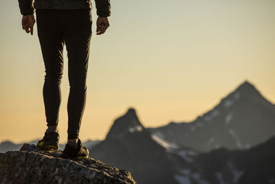 Lower half of trail runner standing on mountain summit with view