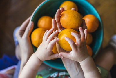 A mother and son place organic oranges in a green bowl.