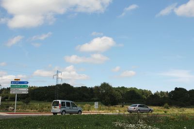 Cars on road against cloudy sky